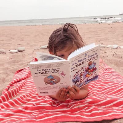 Enfant en train de lire sur la plage