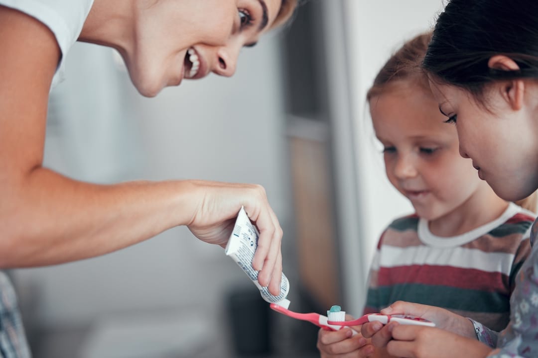 Maman qui distribue du dentifrice à ses enfants