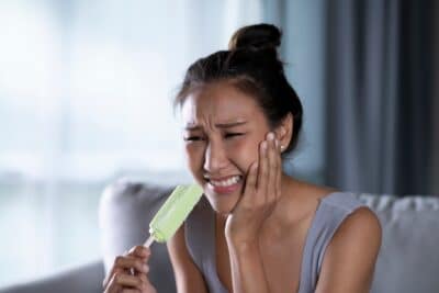 Femme qui a mal aux dents en mangeant une glace