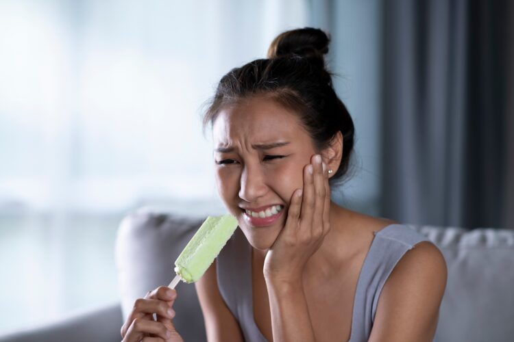 Femme qui a mal aux dents en mangeant une glace
